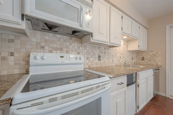 a kitchen with granite countertop white cabinets and white appliances