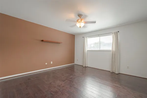 an empty room with wooden floor chandelier fan and windows