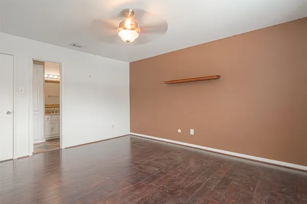 an empty room with wooden floor and chandelier fan
