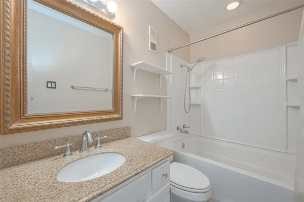 a bathroom with a granite countertop sink toilet mirror and shower