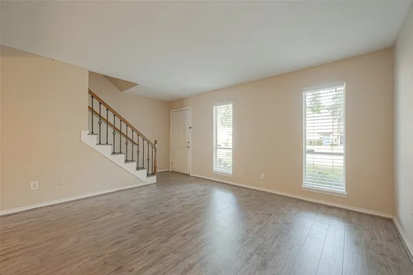 a view of an empty room with wooden floor and a window