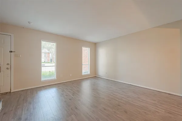 a view of an empty room with wooden floor and window