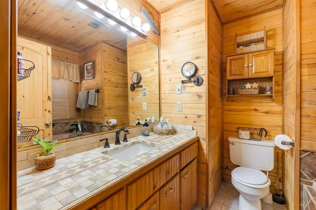 a bathroom with a granite countertop sink mirror vanity and toilet