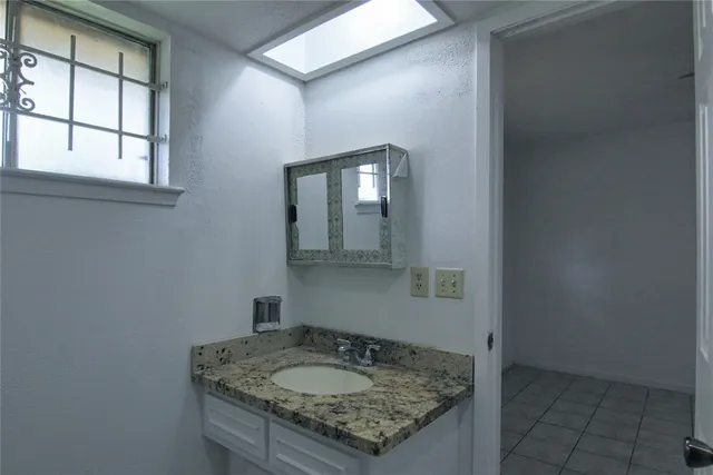 a bathroom with a granite countertop sink and window