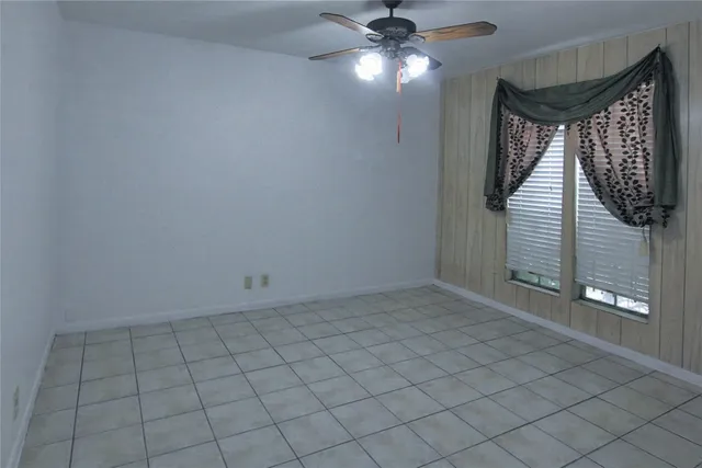 a view of an empty room and chandelier fan