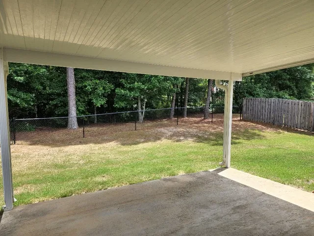a backyard of a house with plants and large tree