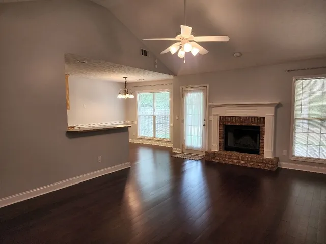 an empty room with wooden floor fireplace and windows