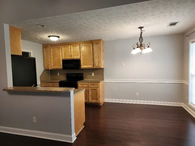 a view of kitchen with granite countertop cabinets and refrigerator