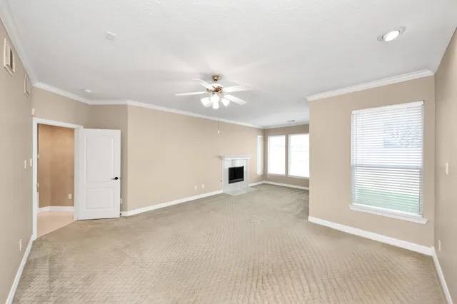 an empty room with chandelier fan and windows