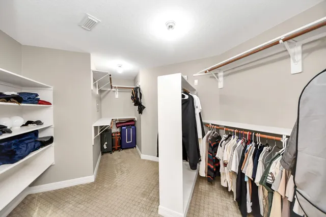a view of walk in closet with clothes and shoes