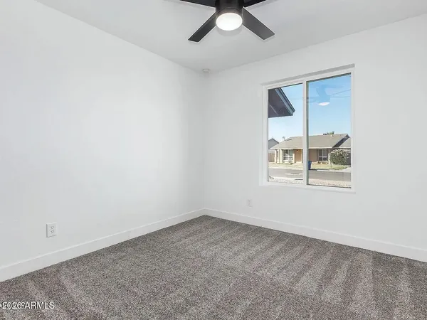 an empty room with a window and a ceiling fan