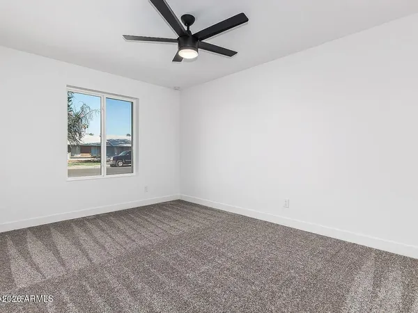 an empty room with a window and a fan