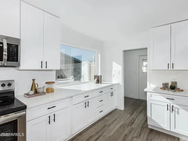 a kitchen with white cabinets and sink