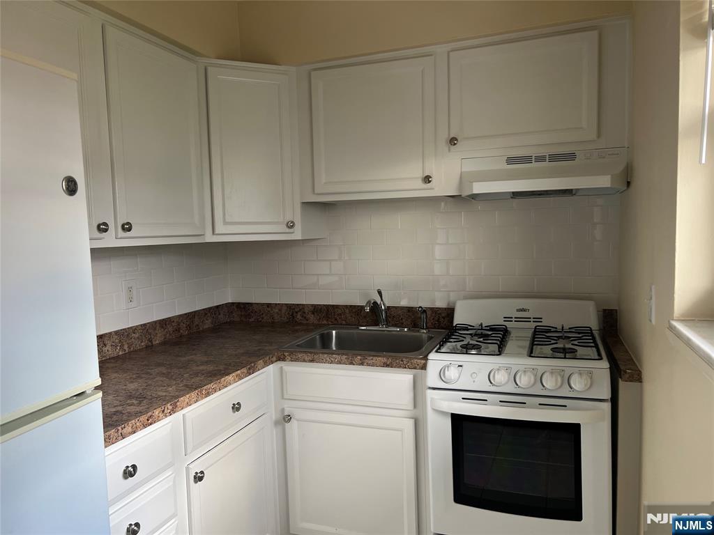 275 River Road, Unit K Bogota, NJ 07603 - Photo 5 of 8 a kitchen with granite countertop white cabinets and white stove