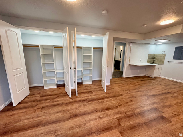 665 West State Road Lehi, UT 84043 - Photo 20 of 30 Spacious room featuring wood-finish flooring, two built-in closet systems with shelving and hanging rods, a built-in desk with lower cabinetry, and recessed lighting