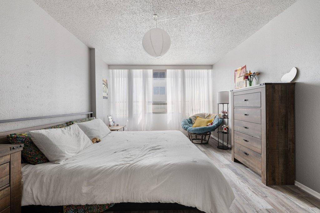 1800 Lavaca Street, Unit 207 Austin, TX 78701 - Photo 11 of 24 Bedroom featuring a textured wall, light wood finished floors, and a textured ceiling