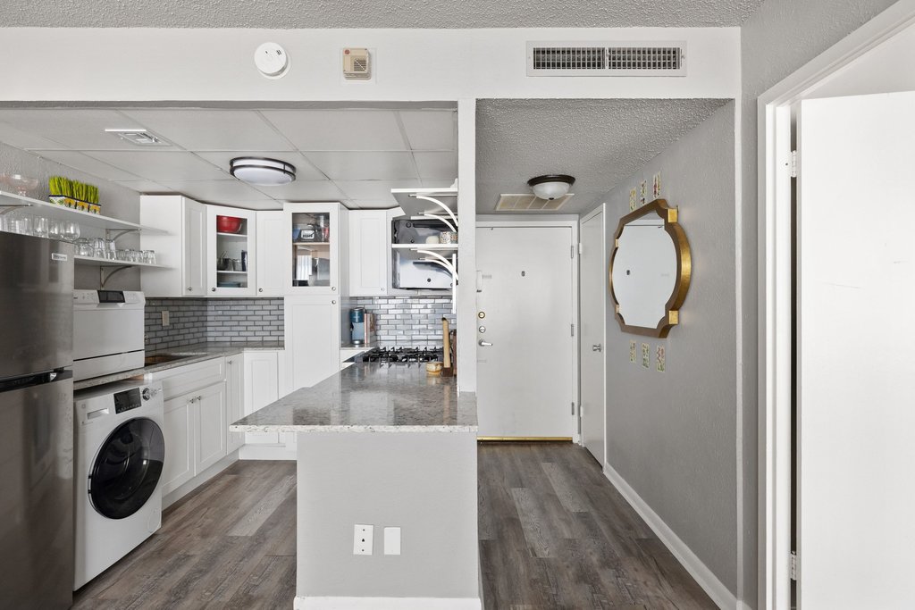 1800 Lavaca Street, Unit 207 Austin, TX 78701 - Photo 14 of 24 Kitchen featuring open shelves, white cabinets, freestanding refrigerator, and washer / clothes dryer
