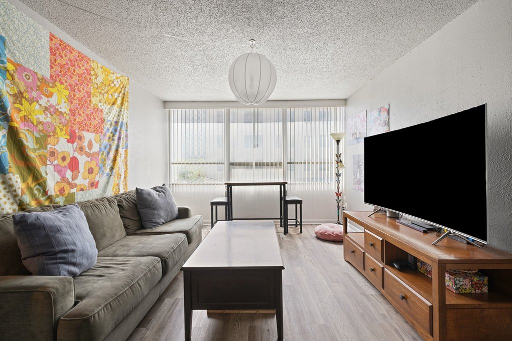 1800 Lavaca Street, Unit 207 Austin, TX 78701 - Photo 2 of 24 Living room featuring light wood-style floors, a textured ceiling, and floor to ceiling windows