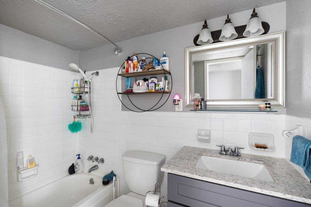 1800 Lavaca Street, Unit 207 Austin, TX 78701 - Photo 21 of 24 Full bath with shower / bath combo with shower curtain, a textured ceiling, vanity, and tile walls