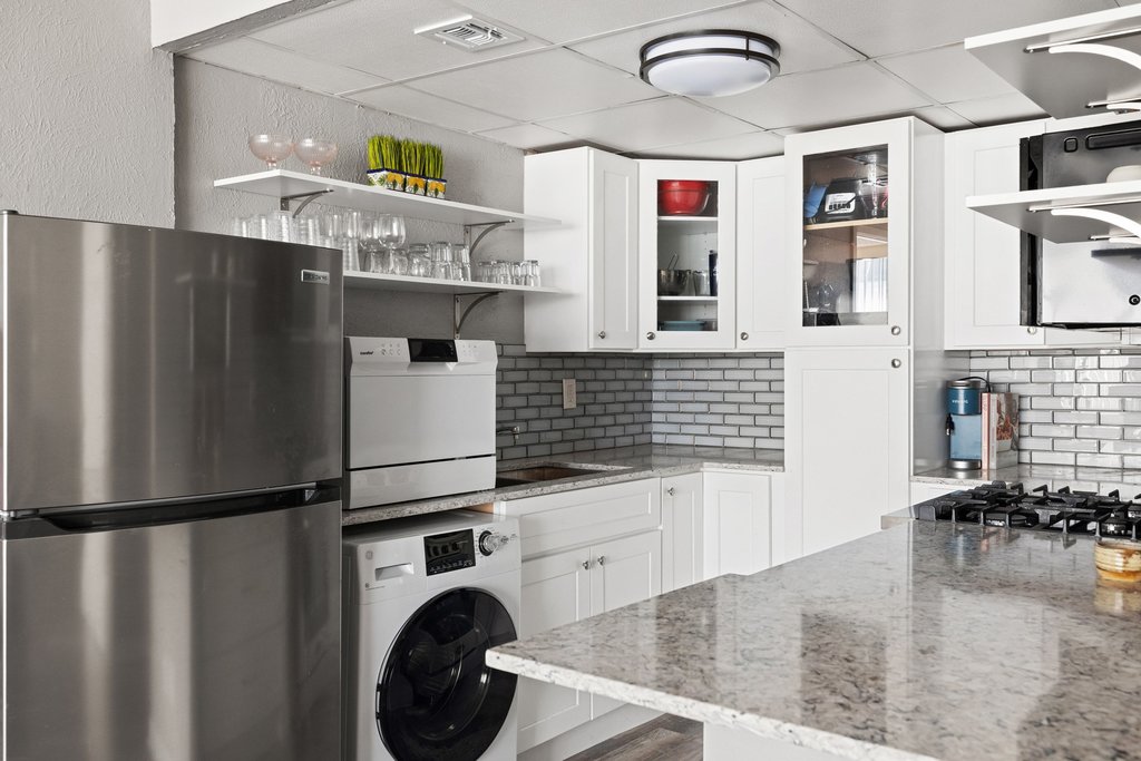 1800 Lavaca Street, Unit 207 Austin, TX 78701 - Photo 3 of 24 Kitchen with stainless steel appliances, open shelves, light stone counters, washer / dryer, and a paneled ceiling