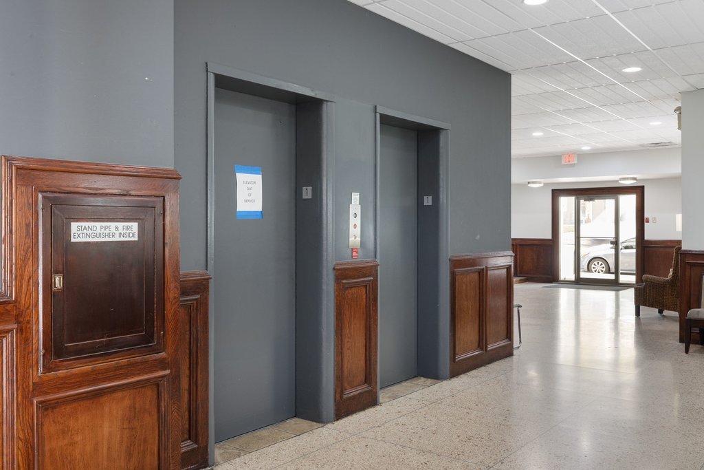 1800 Lavaca Street, Unit 207 Austin, TX 78701 - Photo 9 of 24 Corridor with a wainscoted wall, elevator, dark aggregate flooring, recessed lighting, and a drop ceiling