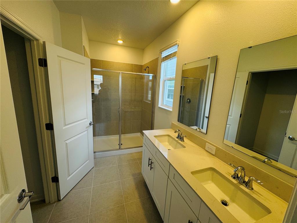 1952 Rider Rain Lane Apopka, FL 32703 - Photo 19 of 34 a bathroom with a double vanity sink a mirror and a bathtub