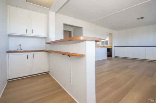 a view of a kitchen with white cabinets and wooden floor