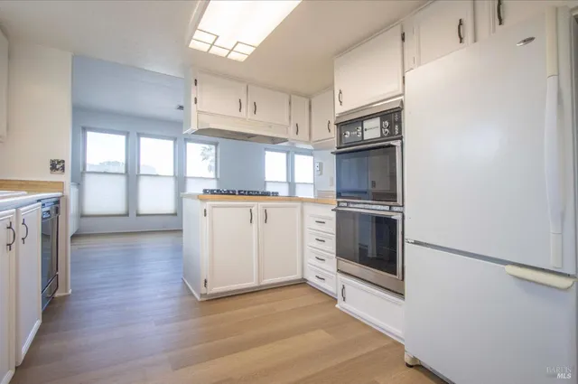 a kitchen with granite countertop a refrigerator and a stove top oven