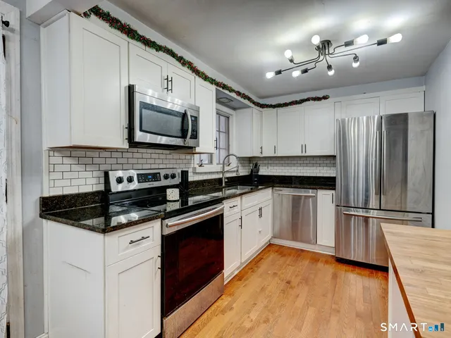 a kitchen with stainless steel appliances granite countertop a stove a sink and a microwave