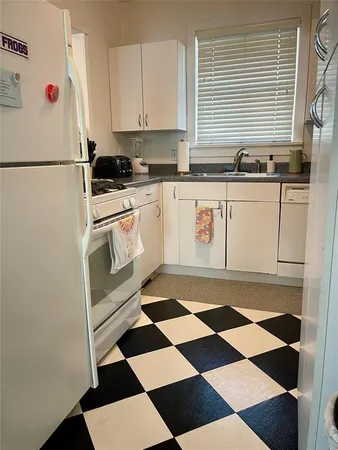 a kitchen with a checkered floor and white cabinets
