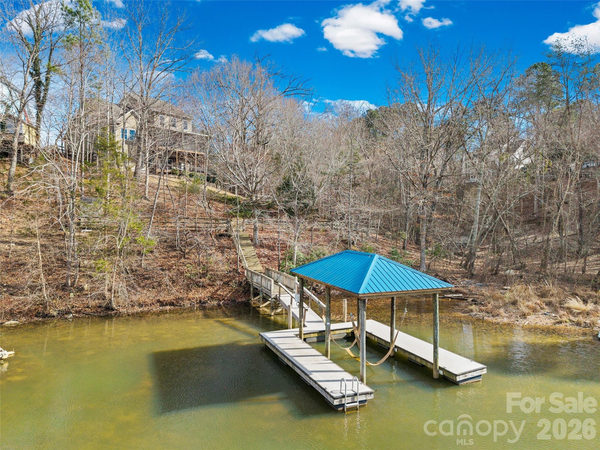 12039 Spinnaker Drive Tega Cay, SC 29708 - Photo 3 of 48 a blue swimming pool with lawn chairs under an umbrella