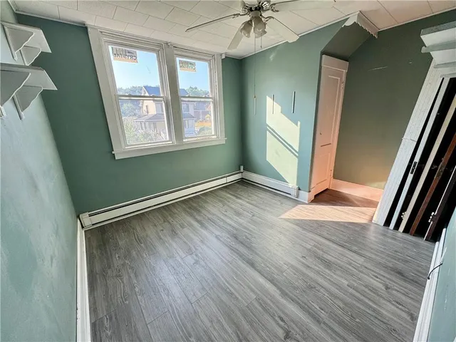 an empty room with wooden floor fan and windows