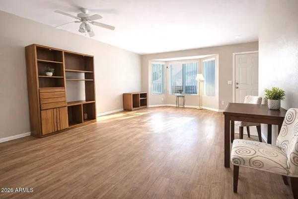 a view of empty room with wooden floor and fan
