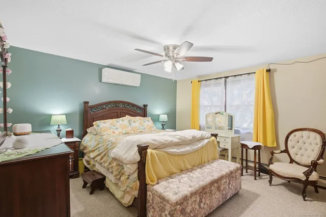 a bedroom with a bed a chair and dresser with wooden floor
