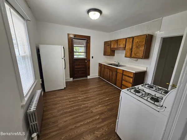 a kitchen with stainless steel appliances a refrigerator a stove a sink and white cabinets