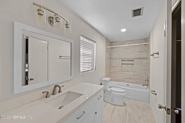 a bathroom with a granite countertop sink a toilet and shower