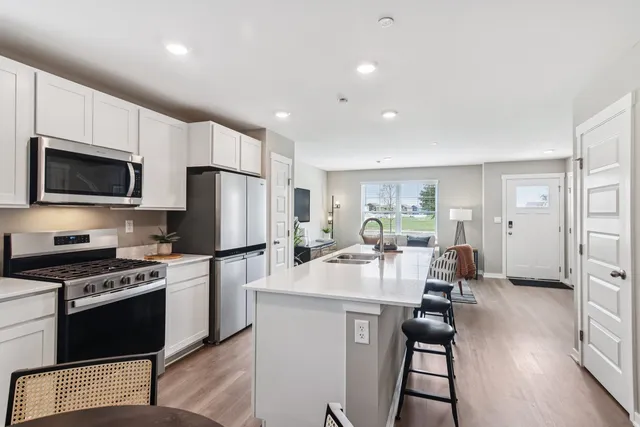 a kitchen with sink a refrigerator and chairs