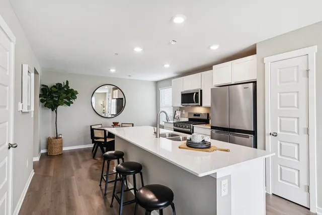 a kitchen with stainless steel appliances kitchen island granite countertop a sink a stove refrigerator and microwave