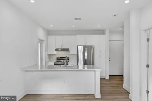 a kitchen with stainless steel appliances a refrigerator and a stove top oven