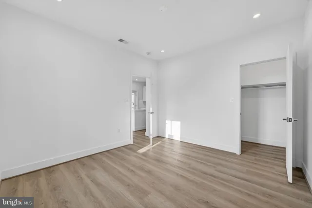 a view of an empty room with wooden floor and closet