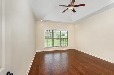 an empty room with wooden floor fan and windows