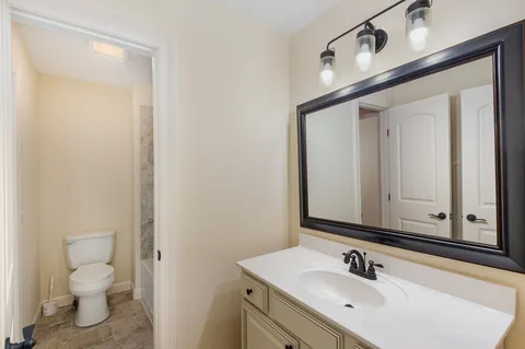 a bathroom with a sink vanity granite and a toilet