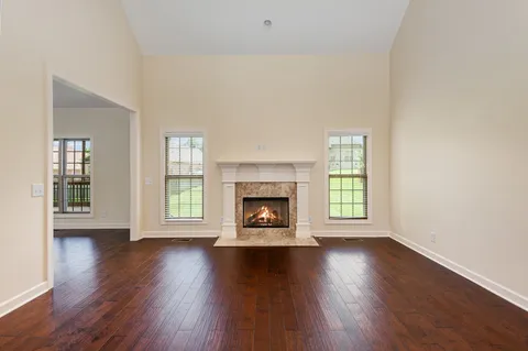 an empty room with wooden floor fireplace and windows