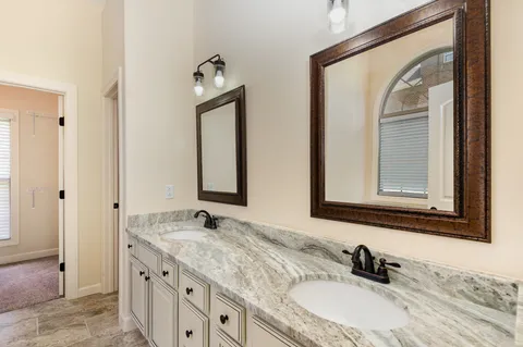 a bathroom with a granite countertop double vanity sink and a mirror