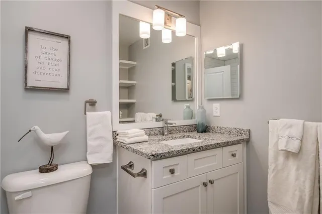 a bathroom with a granite countertop toilet sink and mirror
