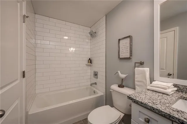 a bathroom with a granite countertop toilet sink and bathtub