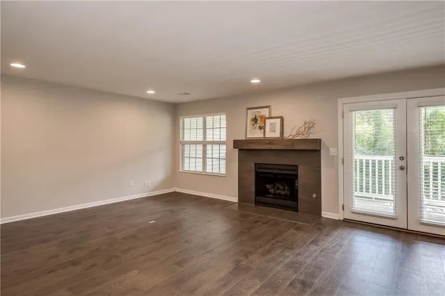 an empty room with wooden floor fireplace and windows