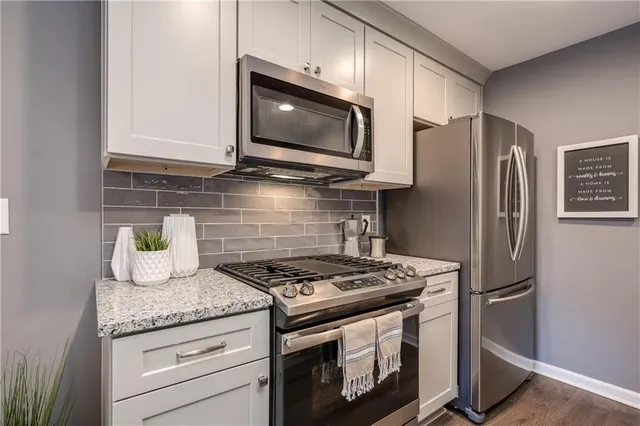 a kitchen with stainless steel appliances granite countertop a stove a refrigerator and a microwave