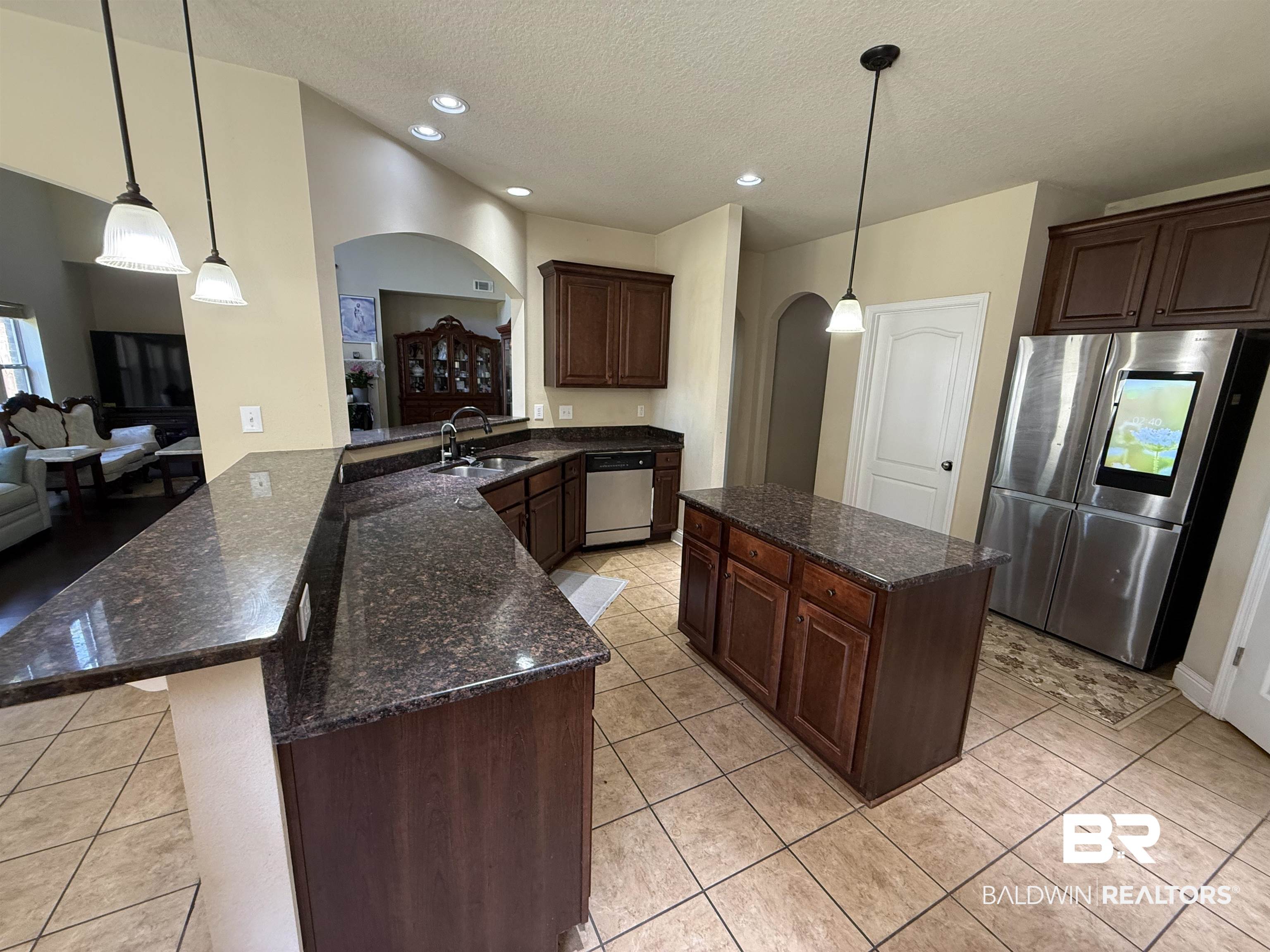 9023 Krystal Ridge Court Daphne, AL 36526 - Photo 17 of 41 Kitchen featuring dark brown cabinetry, stainless steel appliances, a textured ceiling, a center island, and decorative light fixtures
