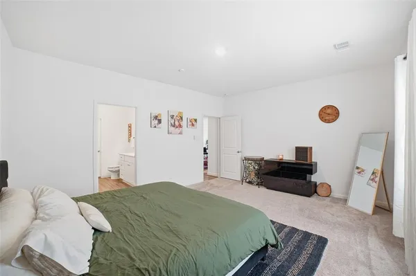 a bedroom with a bed and dresser with wooden floor